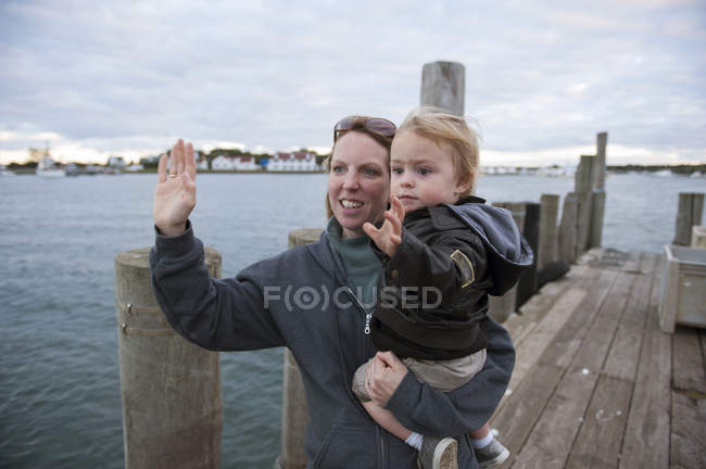 Mother and young son waving on pier — Stock Photo