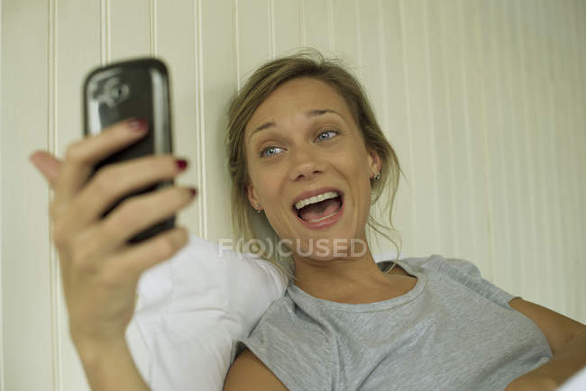 Lächelnde Frau macht Selfie im Bett — Stockfoto