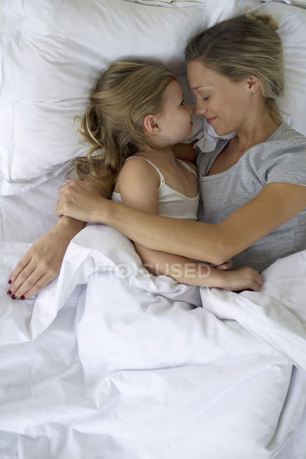 Mère et fille au lit embrassant — Photo de stock