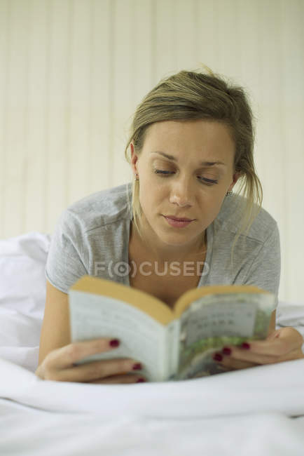 Porträt einer Frau beim Lesen im Bett — Stockfoto