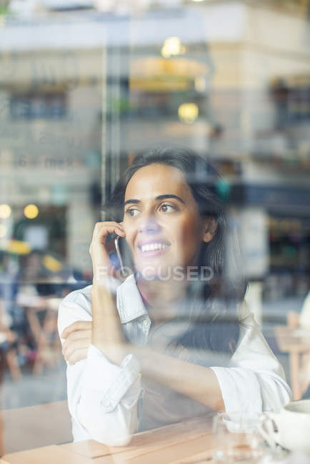 Woman talking on cell phone in coffee shop — Stock Photo