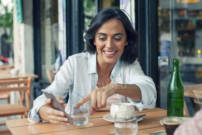 Улыбающаяся женщина смотрит на смартфон — стоковое фото