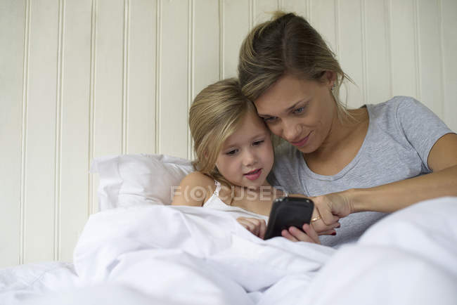 Мать и дочь используют смартфон вместе — стоковое фото