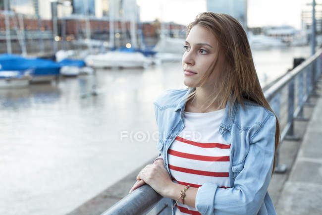 Jeune femme appuyée contre une balustrade, regardant la vue — Photo de stock