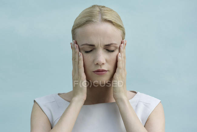 Женщина держит лицо в руках, глаза закрыты — стоковое фото