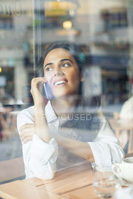 Woman talking on cell phone in coffee shop — Stock Photo