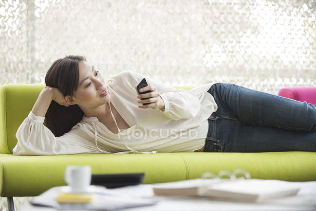 Mujer relajante en casa usando smartphone - foto de stock