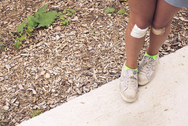 Girl with both knees bandaged — Stock Photo