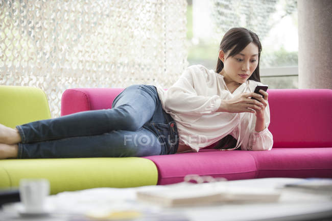 Mujer relajante en casa con smartphone - foto de stock