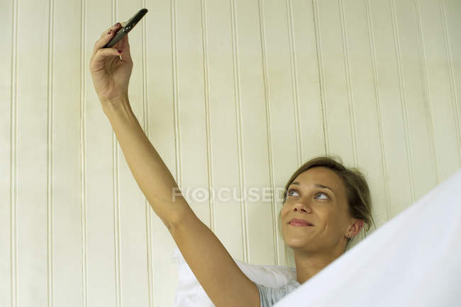Jovem Mulher tomando selfie na cama — Fotografia de Stock