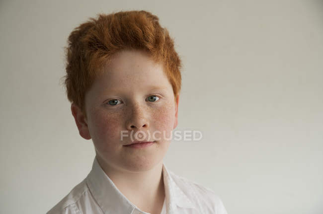 Portrait de Garçon aux cheveux roux et taches de rousseur sur fond gris — Photo de stock