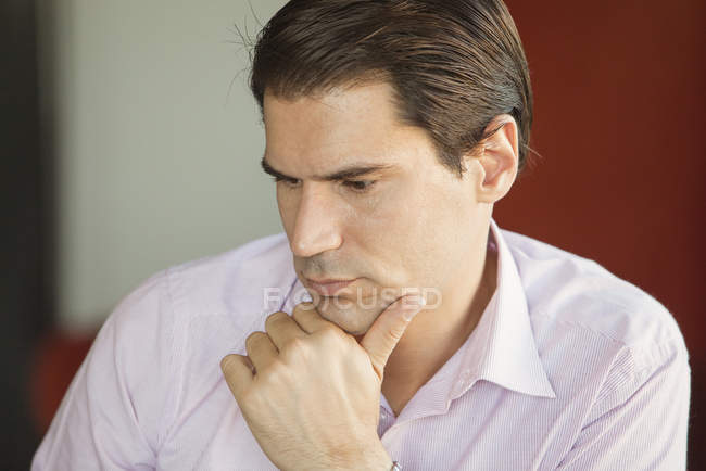 Retrato del hombre de negocios cogido de la mano en la barbilla, sentado en lo profundo del pensamiento - foto de stock