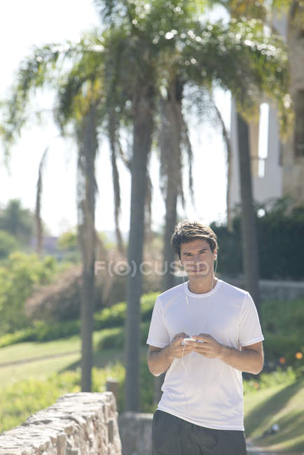 Человек слушает MP3-плеер во время прогулки в парке — стоковое фото
