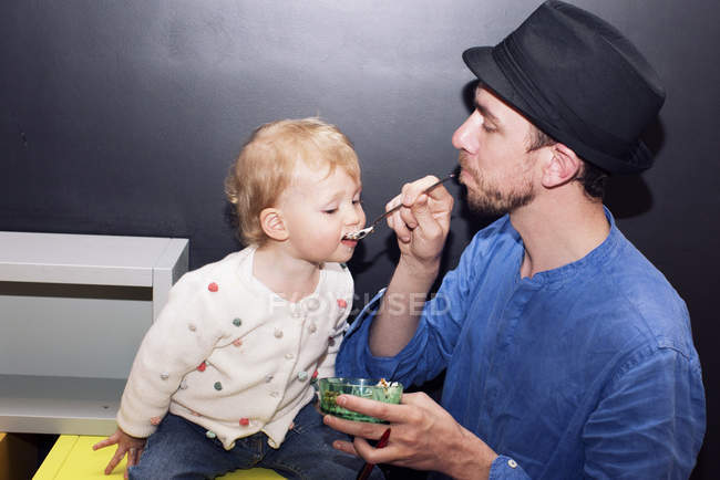 Padre alimentación niño helado con cuchara - foto de stock