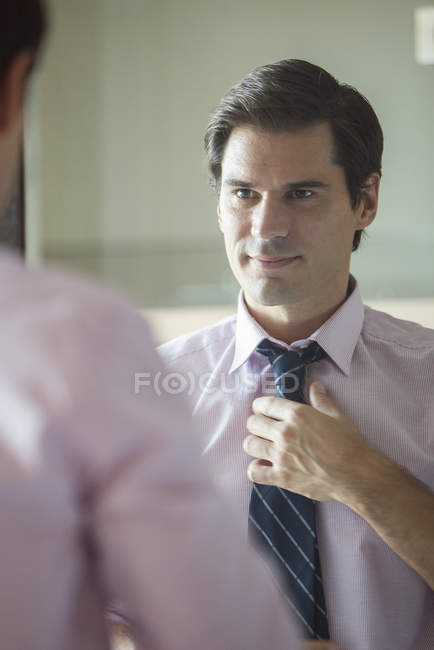 Portrait of Man adjusting his tie in mirror — Stock Photo