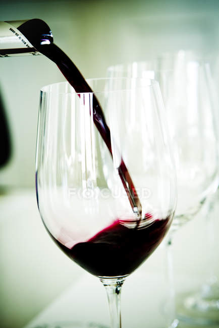 Primer plano de verter vino tinto en la copa - foto de stock