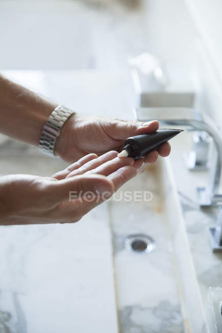 Man squeezing moisturizer out of tube, cropped — Stock Photo