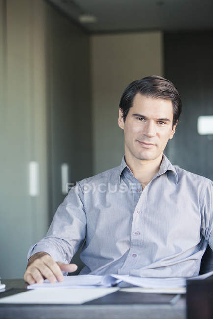 Retrato del hombre de negocios sentado a la mesa en la oficina - foto de stock