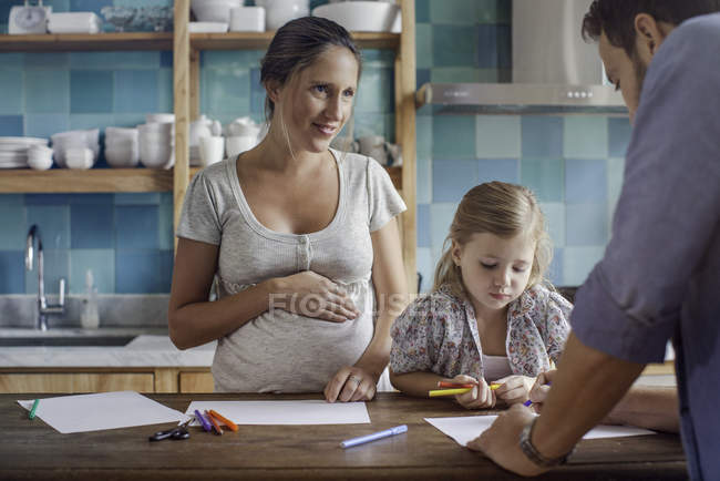 Proud parents watch daughter color coloring book with felt tips — Stock Photo