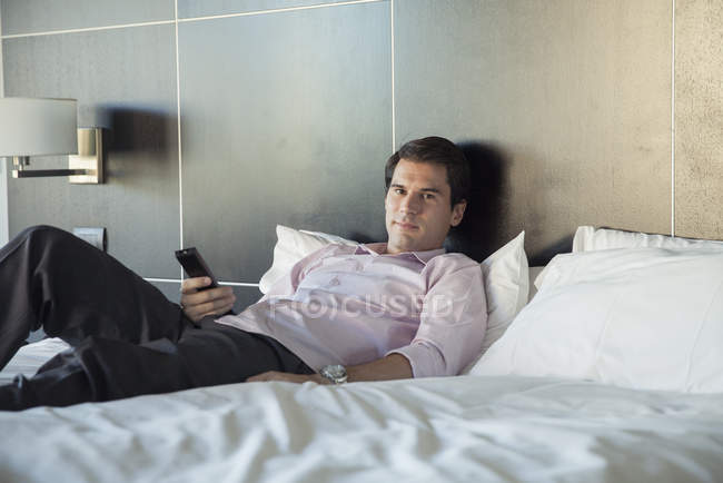 Homme se détendre après le travail en regardant la télévision sur le lit — Photo de stock