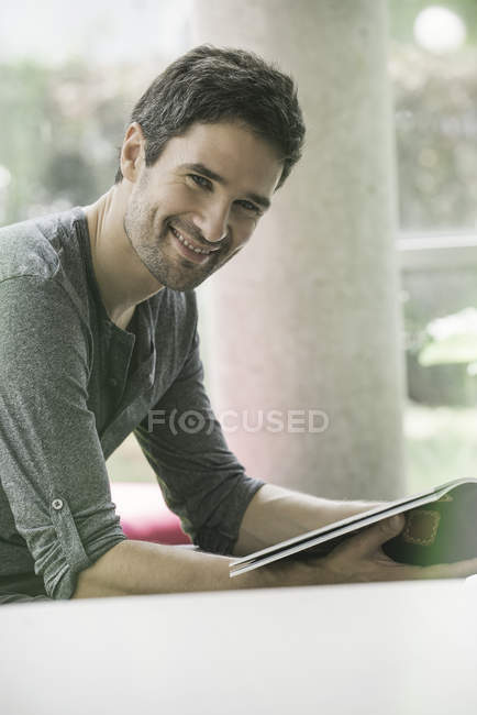 Hombre mirando a través de la revista mientras espera en la sala de espera - foto de stock