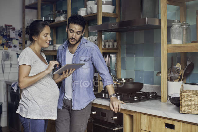 Пара на кухне смотрит на цифровой планшет вместе — стоковое фото