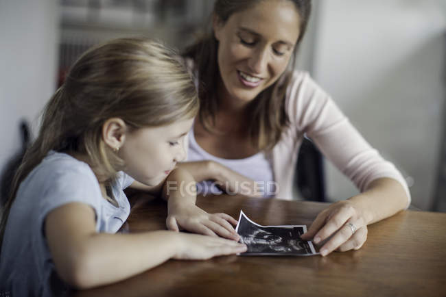 Mother showing daughter ultrasound photo — Stock Photo