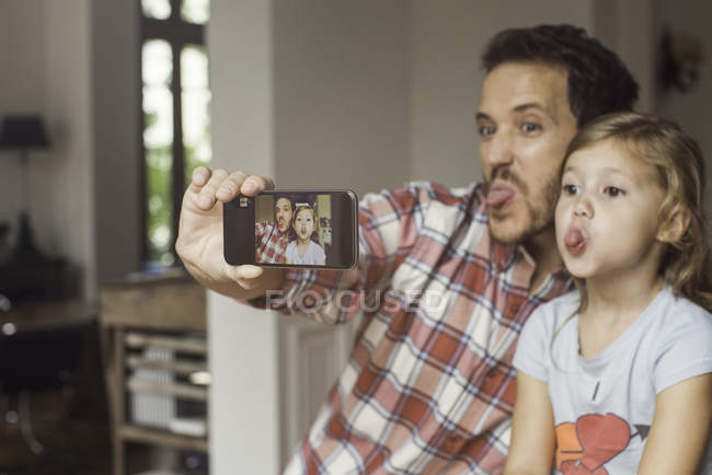 Padre e hija haciendo caras divertidas selfie - foto de stock