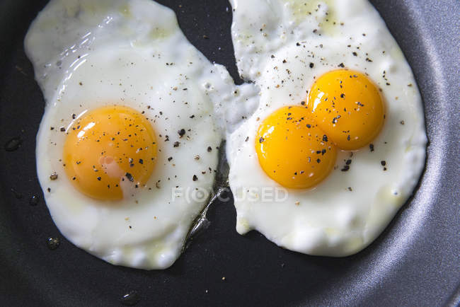 Close up of fried eggs on the frying pan with spices — Stock Photo