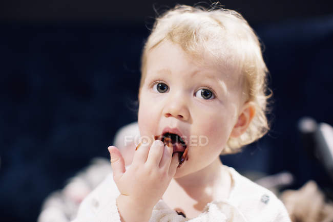Tout-petit léchant le sirop de chocolat des doigts — Photo de stock