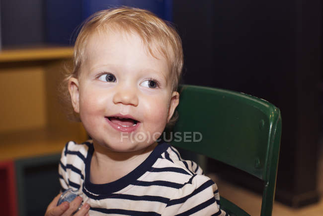 Retrato de niño sonriente sentado en la silla - foto de stock