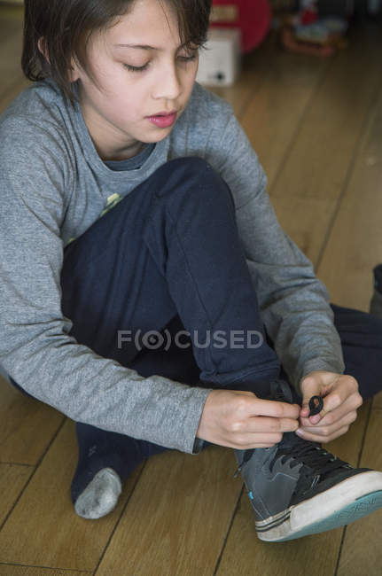 Хлопчик зав'язує шнурки на своєму взутті — стокове фото