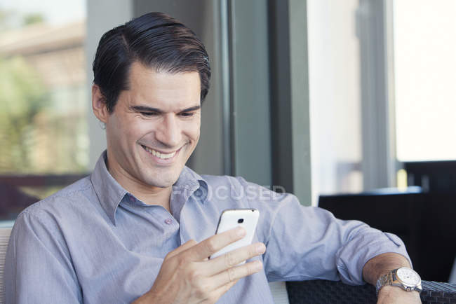 Uomo utilizzando smartphone e sorridente allegramente — Foto stock