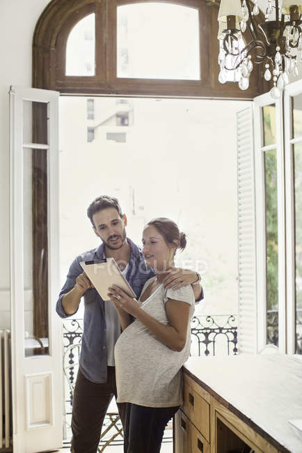 Couple à la maison regardant tablette numérique ensemble — Photo de stock