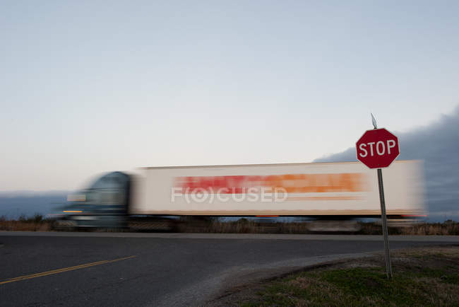 Semi caminhão em movimento na estrada perto de sinal de parada — Fotografia de Stock