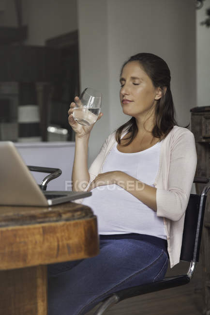 Mulher grávida bebendo água do copo — Fotografia de Stock