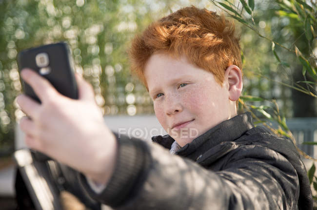 Garçon à l'aide d'un smartphone pour prendre un selfie — Photo de stock