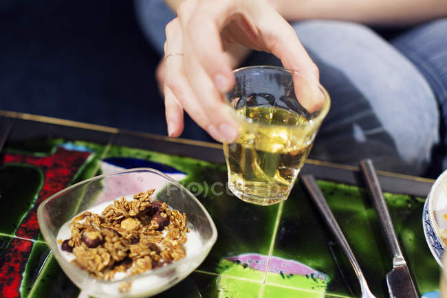 Woman holding glass of apple juice with cereal for breakfast — Stock Photo