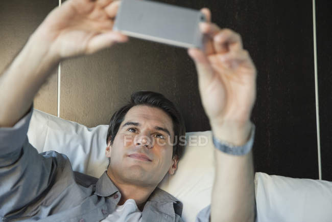 Homme utilisant un smartphone pour prendre un selfie — Photo de stock