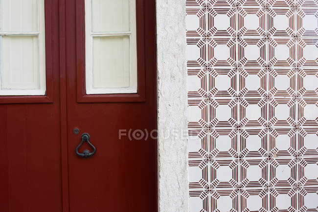 Puerta roja y pared de azulejos ornamentados, Lisboa, Portugal - foto de stock