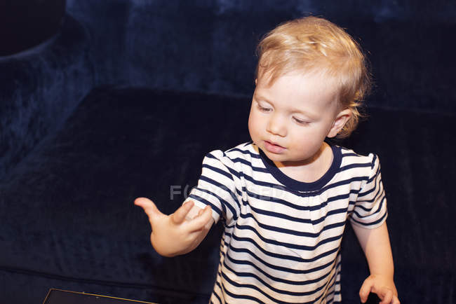Retrato de un niño pequeño mirando a la mano maravillado - foto de stock