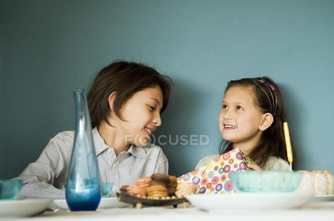 Siblings at birthday party sitting at the table — Stock Photo