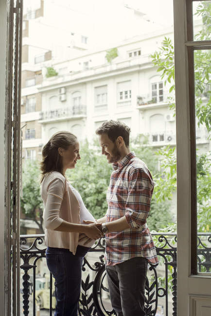 Young couple expecting child standing on the balcony — Stock Photo