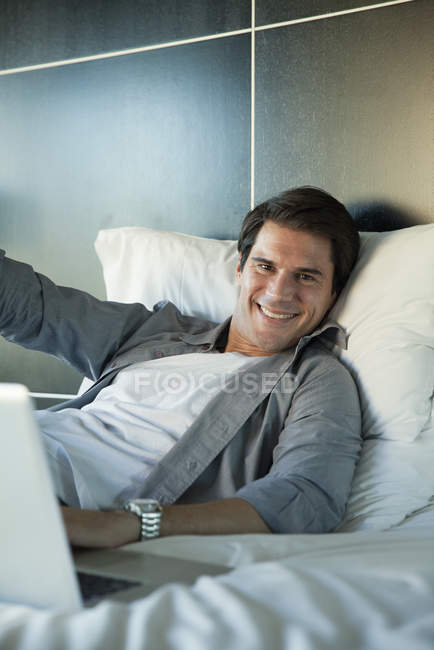 Retrato del hombre sonriente acostado en la cama - foto de stock