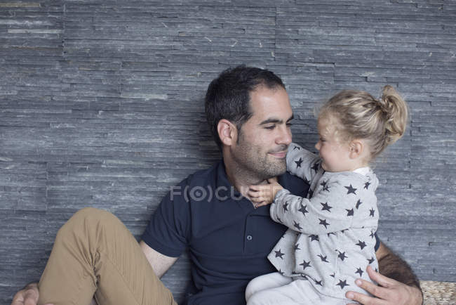 Portrait of father and young daughter against wooden wall — Stock Photo