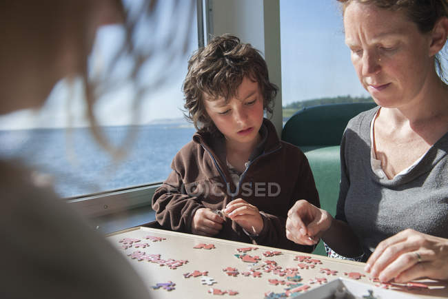 Família montando quebra-cabeças juntos no café — Fotografia de Stock