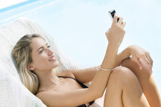Frau entspannt mit Smartphone am Pool — Stockfoto