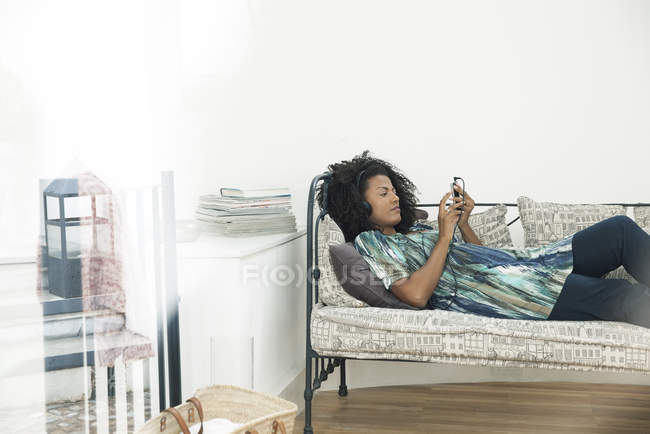 Frau schreibt SMS, während sie sich zu Hause entspannt — Stockfoto