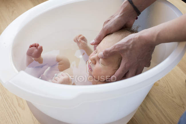Mother hands bathing infant baby — Stock Photo