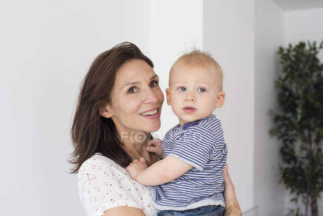 Retrato de feliz madre sosteniendo bebé niño - foto de stock